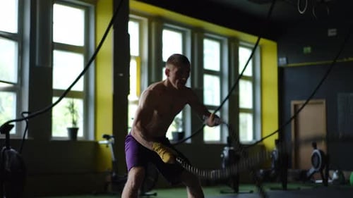 Engaging in an Intense Training Session Utilizing Battle Ropes at a Local Gym Facility