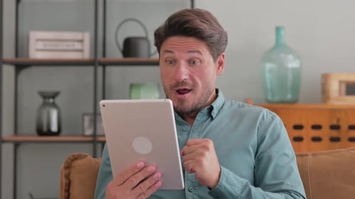 Man Celebrating Good News on Tablet at Home