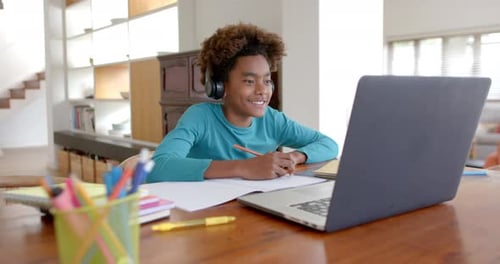 Teen Focused on Homework at Desk With Laptop