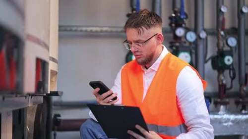 Concerned Engineer Inspects Industrial System Using Smartphone