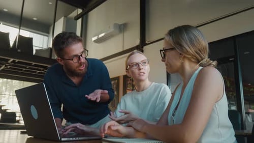 Three Colleagues Brainstorming Discussing a Project Collaborating Around Laptop in Modern Office