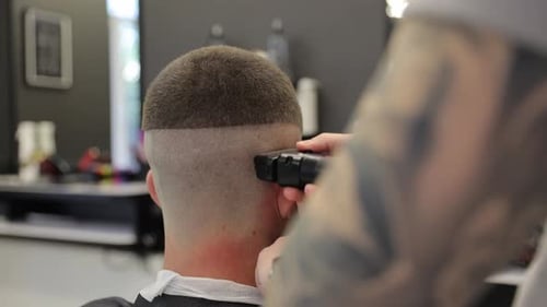Friseur rasiert einem Kunden mit einer professionellen elektrischen Haarschneidemaschine in einem modernen Friseurladen den Kopf
