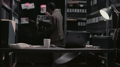 Man Reviewing Evidence in Dark Office at Desk