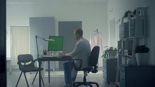 Doctor consults patient online using green screen computer in modern hospital office