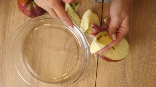 Woman Slicing an Apple into Pieces on a Wooden Table