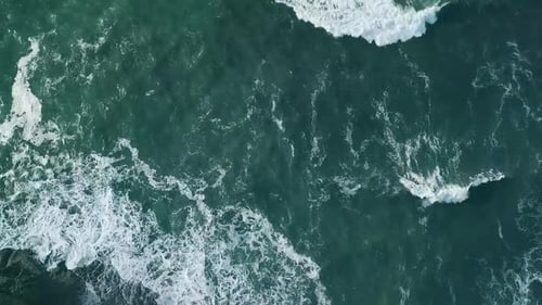 Aerial view of the ocean showcasing waves, deep blue water, and natural sea patterns from above.