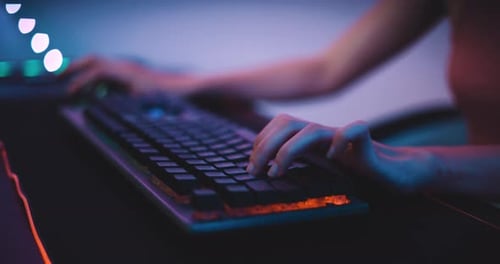 Junge asiatische Esport-Gamer spielen zu Hause Online-Videospiele am Computer mit Neonlicht