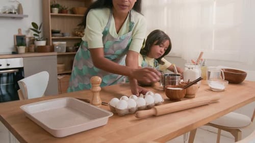 Girl and Adult Baking Together in Bright Kitchen