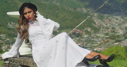 A young girl dressed in antique bridal attire on the grounds of a crumbling fortress.