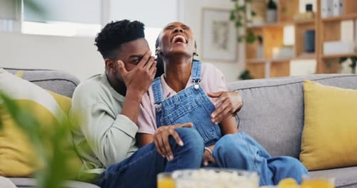 Movie, horror and couple hug watching tv on a sofa, happy and playful in their home together