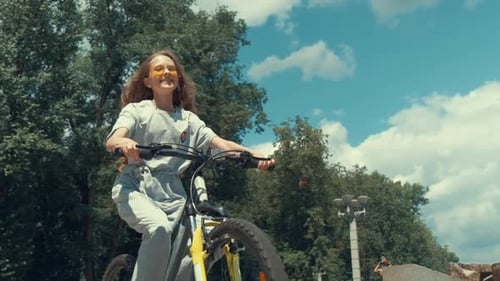 Bottom View of a Girl in Fashionable Sunglasses Rides a Bicycle Slow Motion