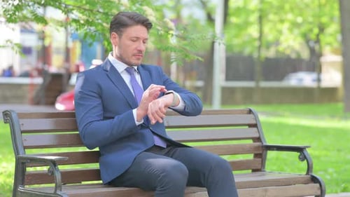 Man in Suit Checking Smart Watch in Park