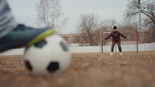 Low Perspective of Player Approaching Goal with Ball Green Jacket Attacker Feinting Past Keeper