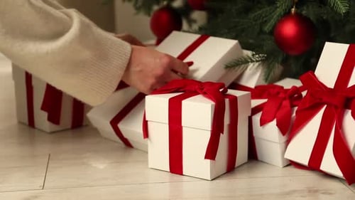 Woman adjusting bow on Christmas gifts at home, closeup