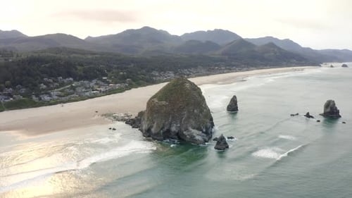 4k aerial of haystack rock in canon beach oregon. West coast beach drone shot.