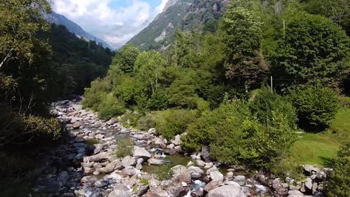 Cinematic drone shot over river, close to the trees and over the mountains.