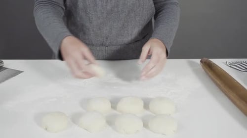 Woman Rolls Dough With Rolling Pin at Table