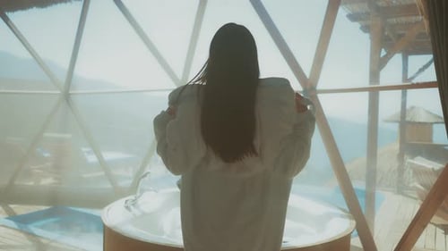 Woman relaxing in a hot tub inside a geodesic dome with mountain views