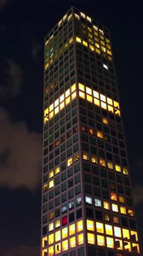 Top of the skyscraper with lights in the windows. Drone footage rising along the building