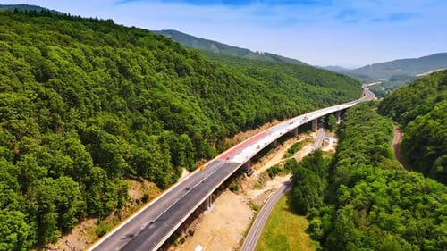 Building of the freeway at the foot of green wooded mountains.