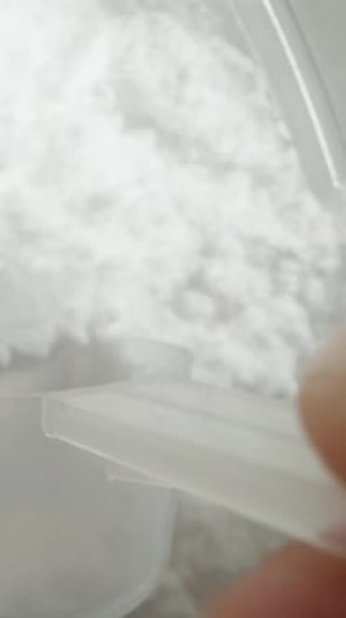 Vertical video. Slow motion, pov macro video. Holding a measuring spoon, I scoop white powder.