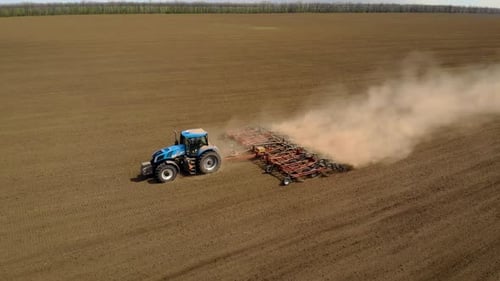 Aerial View of Blue Tractor Plowing Dusty Soil in Field Farmer Cultivating Arable Area for Seeding