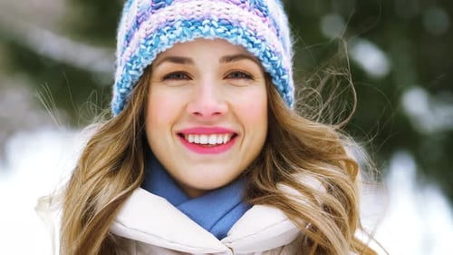 Smiling woman in winter hat outdoors in snow