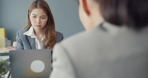 Asia businesswomen using laptop on table working and communicate sitting on office desk.