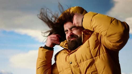 Young Traveler Struggling with Cold Winds on Top of the Mountain