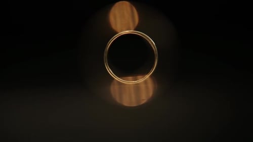 Gold Wedding Ring is Illuminated with Light on Black Background