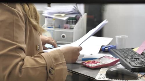 Unrecognizable woman in coat prepare documents in office before leaving for meeting