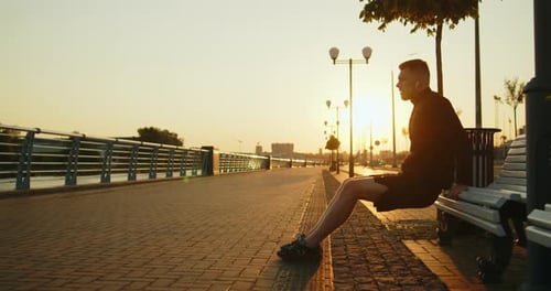 Young Athlete Doing Reverse Pushups From a Bench on a City Street at Sunset