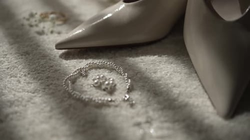 Close-up of bridal accessories including pearl bracelet, earrings, and shoes on soft carpet.