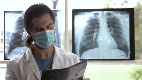Beau technicien en rayons X vérifiant soigneusement la radiographie de la région thoracique