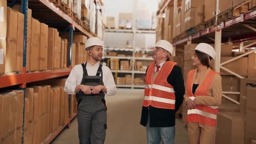 An attractive man in a work uniform shows the range on the territory of the warehouse