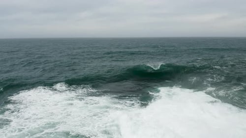 Wave breaking onto a shallow rock shelf during a storm. Aerial shot flying towards the breaking wave