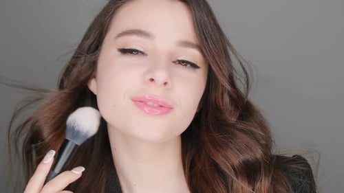 Woman Applies Makeup with Fluffy Brush Close Up