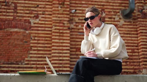 Belle femme profondément absorbée par une conversation téléphonique alors qu'elle est assise à l'extérieur