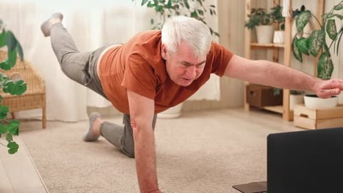 Hombre mayor maduro feliz haciendo ejercicios de gimnasia en casa en línea con una computadora portátil, estilo de vida saludable