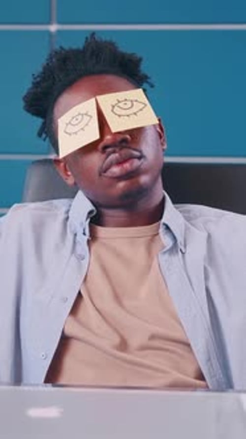 Creative Guy with Funny Sticky Notes on His Eyes During a Break in the Office