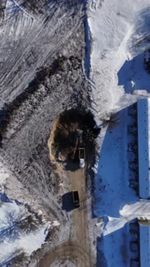 Excavator Digging Hill Vertical Drone Aerial Descending Construction Site Snowy Landscape