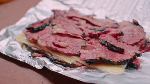 Pastrami meat and cheese on aluminum foil, close up
