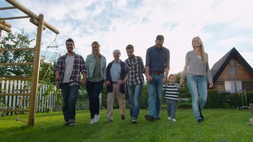 Happy Multi-Generational Family Walking on Grassy Lawn