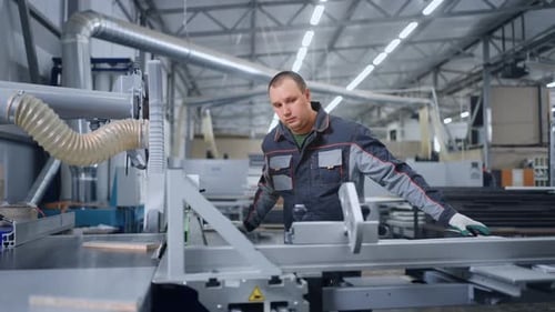 Industrielle Holzbearbeitung in einer Anlage zur Möbelherstellung Männlicher Bediener einer automatischen Sägemaschine