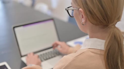 Vista trasera de una mujer escribiendo en la computadora portátil
