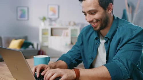 Young Man Working on Laptop and Drinking Coffee