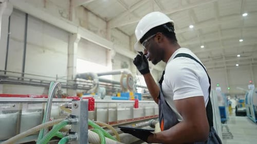 African American Worker in Uniform Checks the Cooling System at the Factory