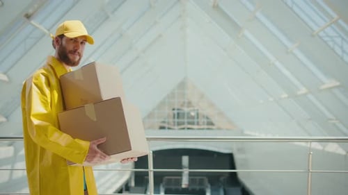 The Courier in Yellow Uniform Passes with the Package in His Hands