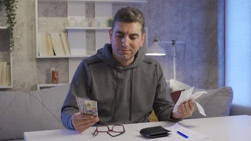 Man Reviewing Bills at Table with Money