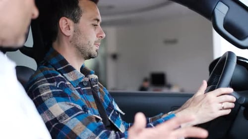 Man Sits in Car Talking with Salesman